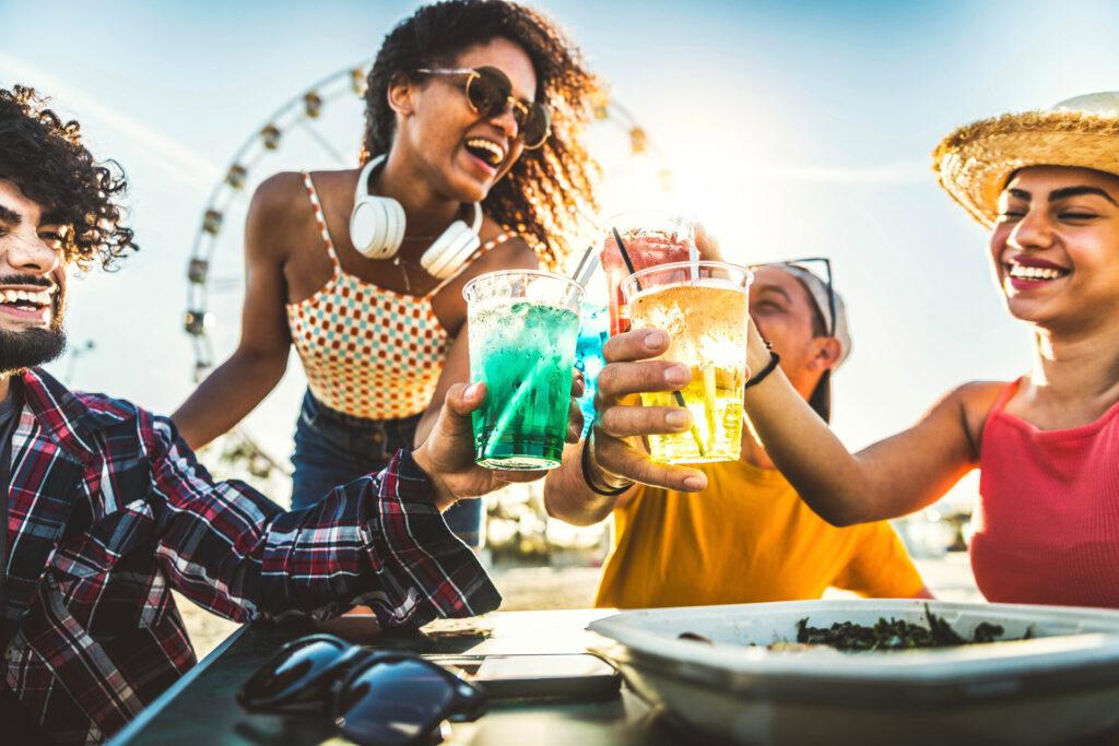 junge Menschen feiern jubelnd mit Cocktailgläsern auf Ibiza