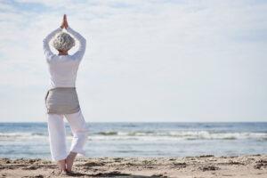 aktive Seniorin macht Yoga am Strand