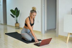 Frau macht Yoga zu Hause mit Laptop.