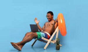 Schwarzer Mann, der in Liege mit Wasserball chillt und auf den Laptop schaut, Online-Verkauf für Pool Zubehör findet