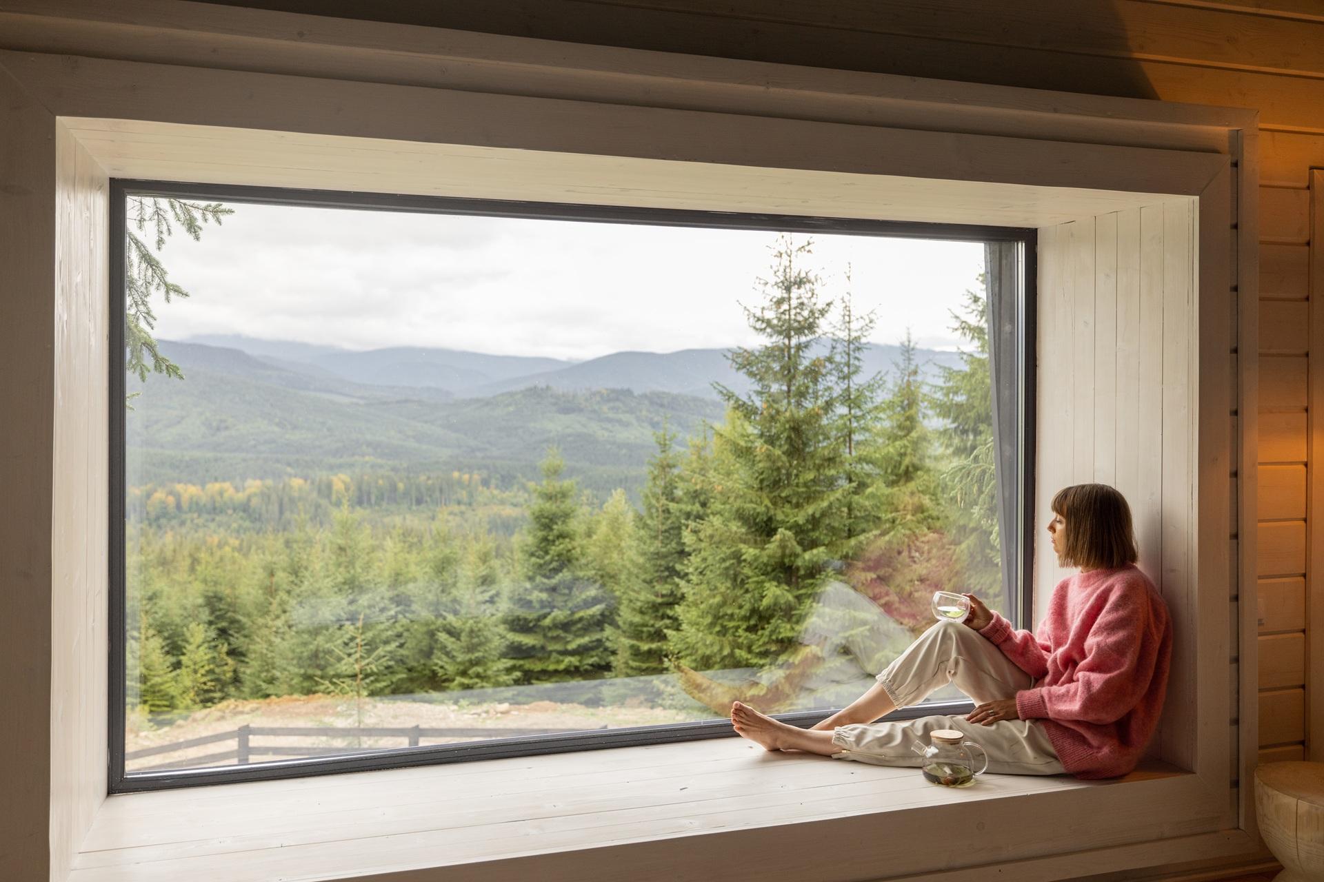 Blick aus gemütlichem Fenster im Holzhaus | Steinwand

