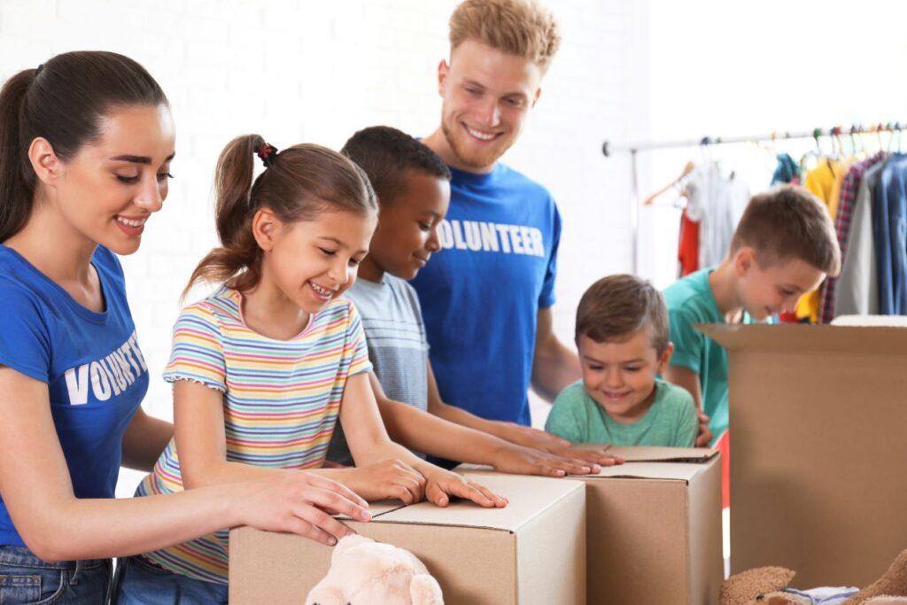 Freiwillige Helfer und Kinder packen gemeinsam Hilfspakete im Rahmen einer Nothilfeaktion – praktische Hilfe fuer Kinder in Not