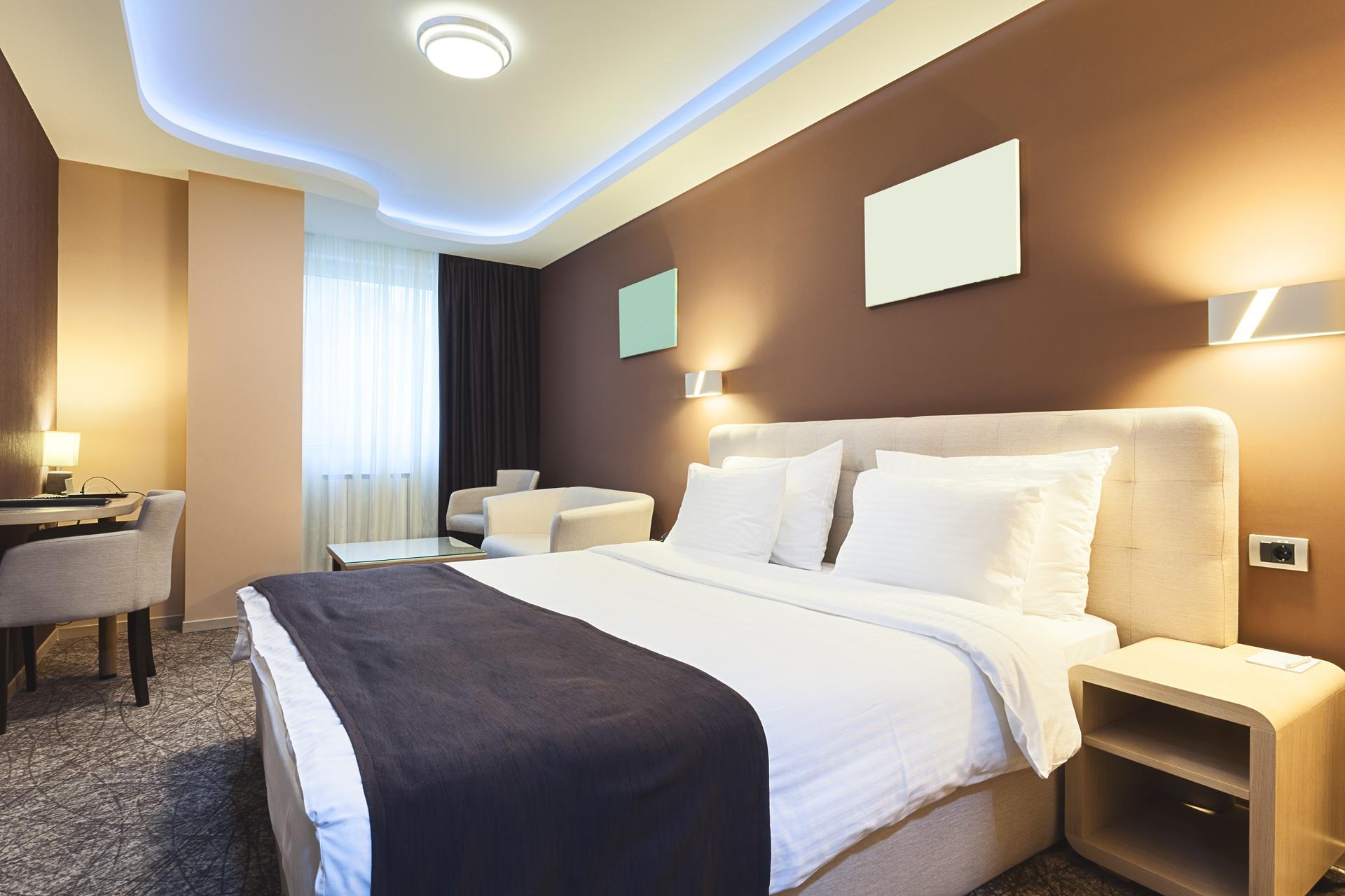 Modern eingerichtetes Hotelzimmer mit Doppelbett | Eckkleiderschrank