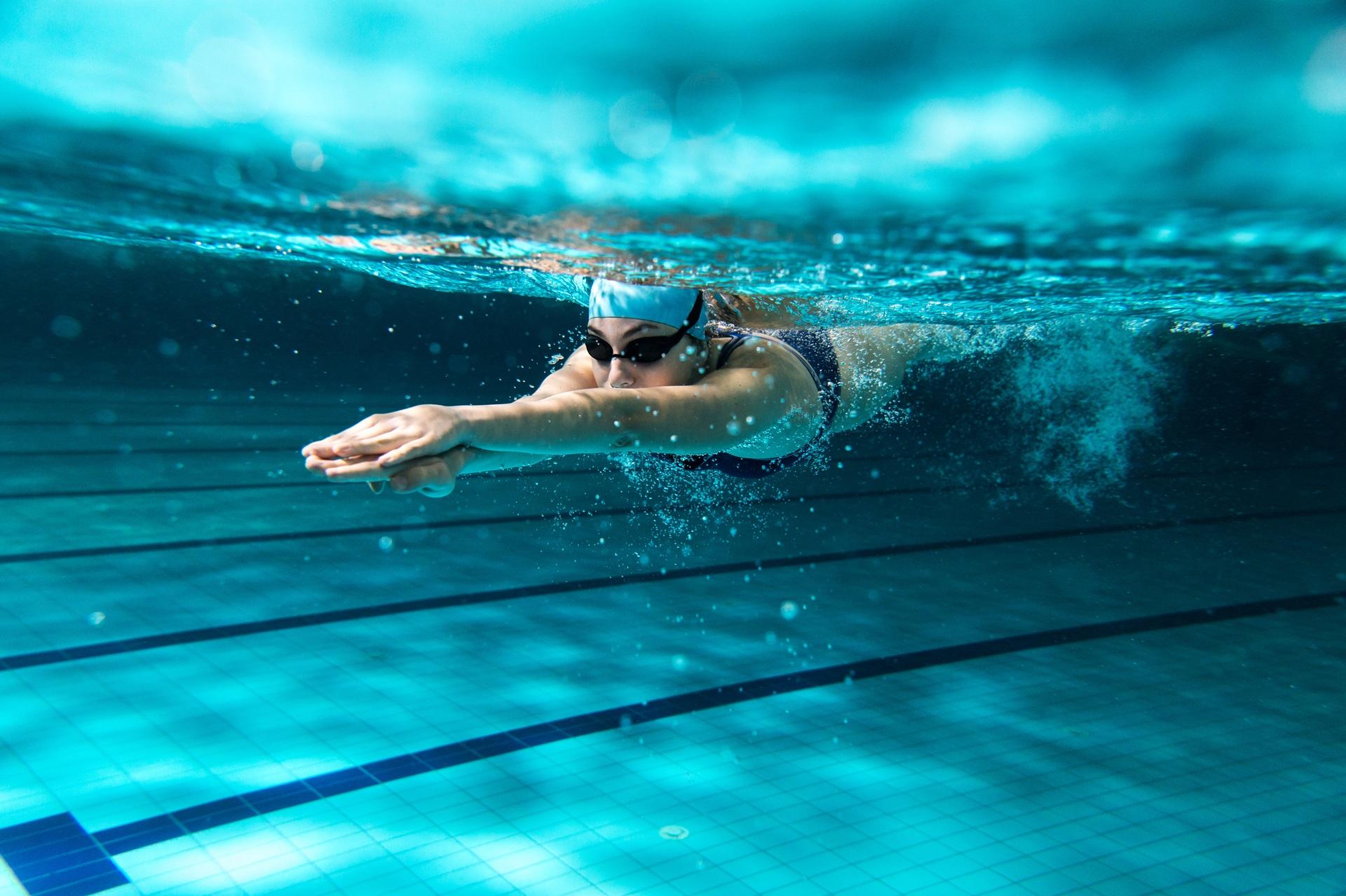 Frau schwimmt unter Wasser in Sportbecken | Inlinehockey